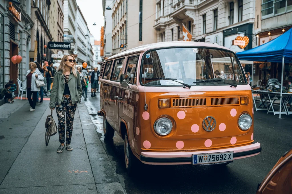 A woman walking past an orange Volkswagen Van