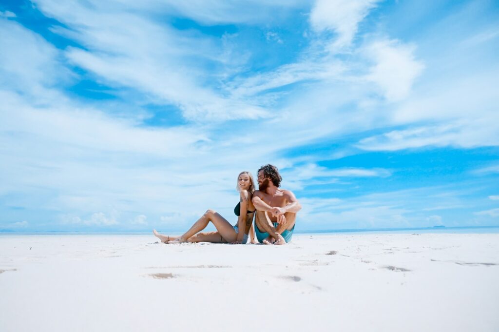 a couple sitting next to each other on a beach