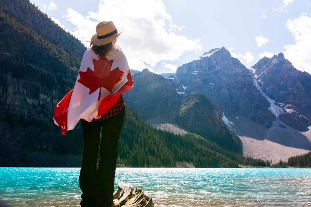 a woman wearing a sun hat and covering herself with a canadian flag