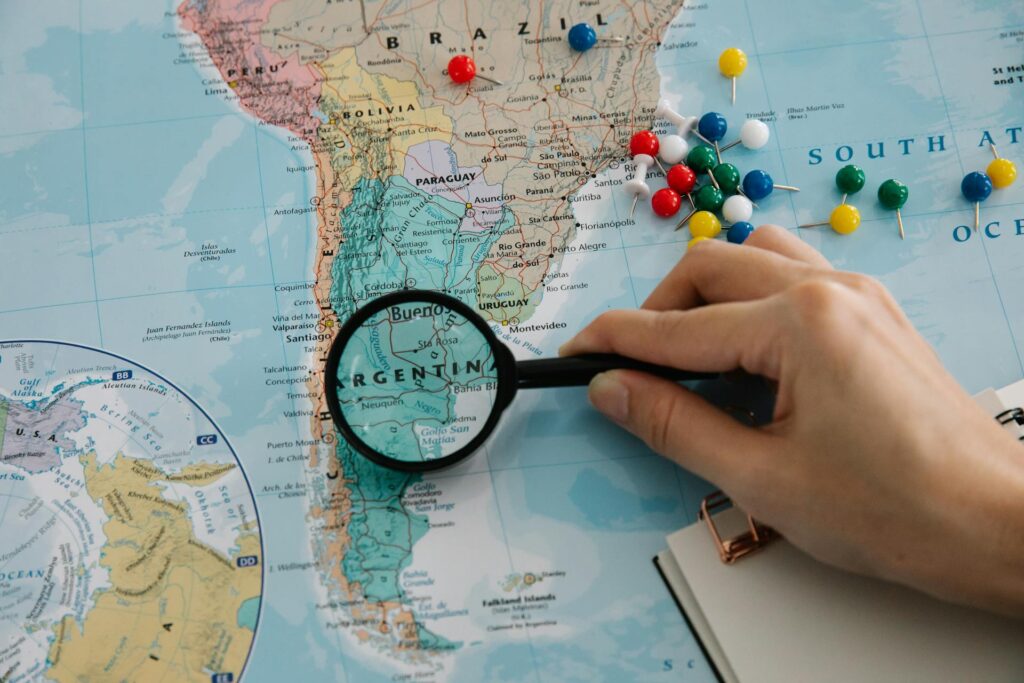 a hand holding a magnifying glass over a map