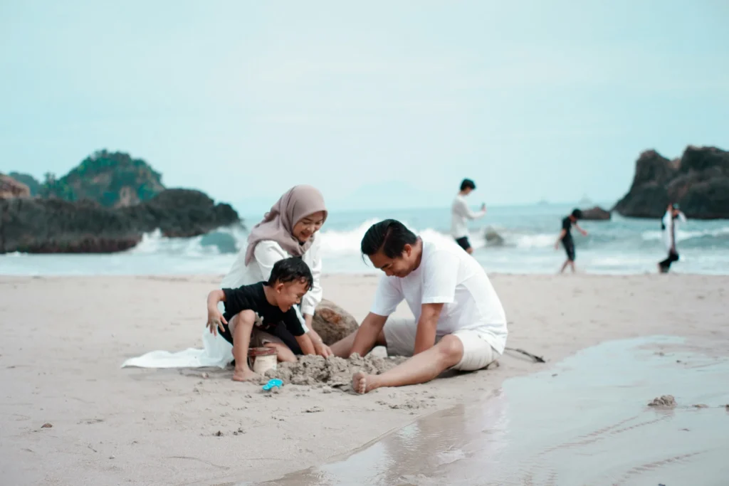 A man, woman, and child digging up sand on a beach