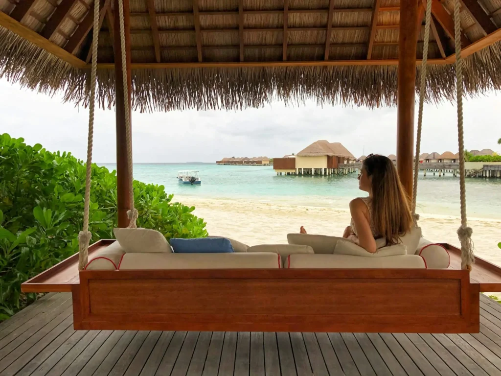a woman relaxing on a hanging bed overlooking the sea