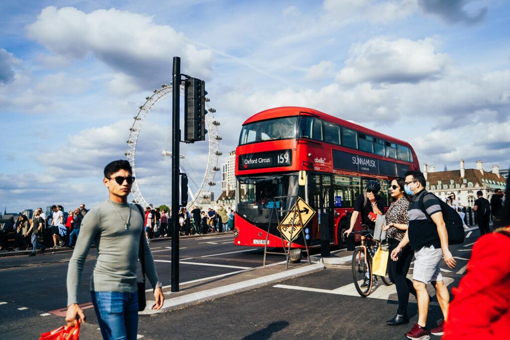 people on a London street with a red double deck bus